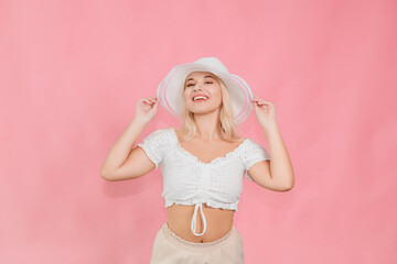 young girl in white hat and clothes posing on pink background