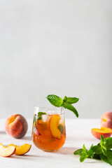 Summer cold peach fizz cocktail or iced tea with mint. Two glasses with peach lemonade on a white background. Summer refreshing drink recipe. Homemade fruit tea with ice. Restaurant menu