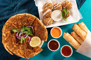 Traditional Moroccan pizza flatbread topped with red lentils, falafel and cheese rolls served with dips