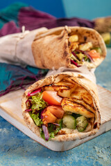 Traditional Mediterranean Arabic grilled halloumi, hummus and vegetables in flatbread wraps topped with herbs and balsamic vinegar