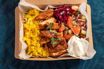 Traditional Eastern Mediterranean takeaway meal of grilled chicken, yellow rice, fresh salad and yoghurt in cardboard - obrazy, fototapety, plakaty