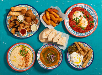 Traditional Eastern Mediterranean Moroccan hot breakfast of fried vegetables, halloumi, falafel, shakshuka, hummus, red lentil and flatbread