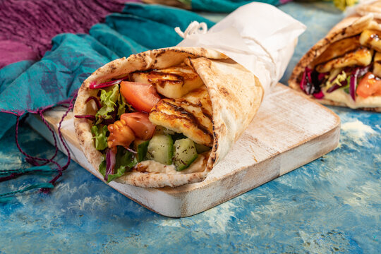 Traditional Mediterranean Arabic grilled halloumi, hummus and vegetables in flatbread wraps topped with herbs and balsamic vinegar