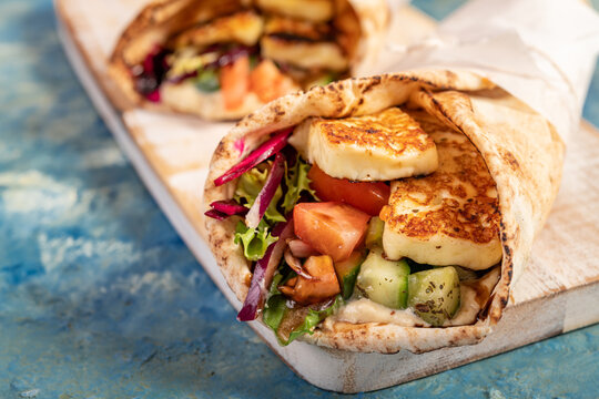 Traditional Mediterranean Arabic grilled halloumi, hummus and vegetables in flatbread wraps topped with herbs and balsamic vinegar