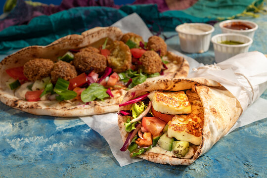 Traditional Mediterranean Arabic grilled halloumi and falafel, hummus and vegetables in flatbread wraps with herbs and sauces