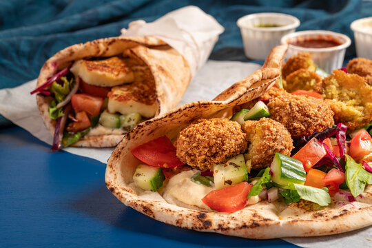 Traditional Mediterranean Arabic grilled halloumi and falafel, hummus and vegetables in flatbread wraps with herbs and sauces