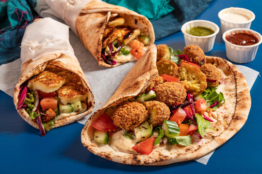 Traditional Mediterranean Arabic grilled halloumi and falafel, hummus and vegetables in flatbread wraps with herbs and sauces