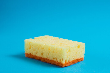 Yellow porous sponge for cleaning on a blue background with copy space. Home cleaning concept
