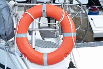 Orange life buoy attached to yacht. Water rescue equipment.