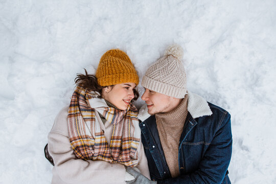 people, love and leisure concept - happy smiling couple lying on snow in winter