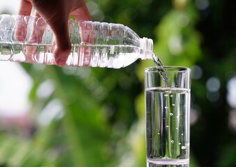 photo of pouring water in a glass of water with green background