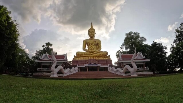 Time lapse Beautiful  Big Golden Buddha statue against sunset clouds sky in Thailand temple,khueang nai District, Ubon Ratchathani province, Thailand.Zoom in.