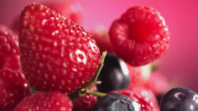 Ripe juicy Strawberry Blueberry Raspberry rolling above many mixed Berries