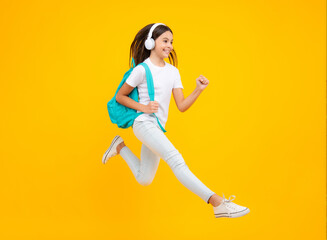Fototapeta na wymiar Happy teenager portrait. School teenager child girl in headphones with school backpack. Teenager student, isolated background. Learning music. Jump and run, jumping child.
