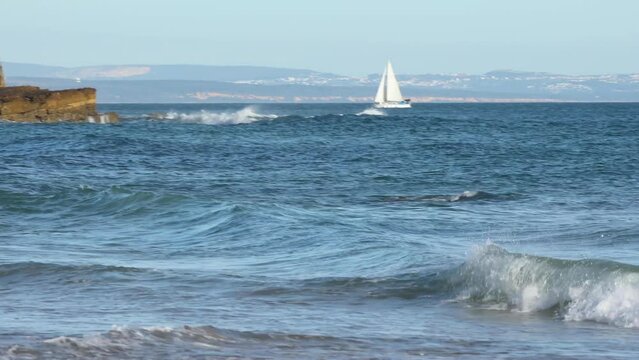 Beautiful white boat sailing towards the Fortress of S&atilde;o Juli&atilde;o Da Barra in Portugal