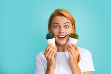 Young beautiful woman holding small cactus pot, smiling happy.