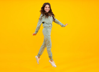 Fototapeta na wymiar Sports studio kids portrait. Cute teenager girl in a purple casual sports suit. Child in a stylish sports suit on yellow background isolated.