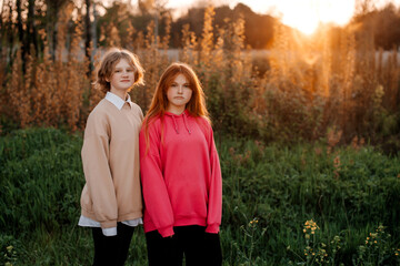 Two girls are standing in the forest against the background of the sunset in the background light