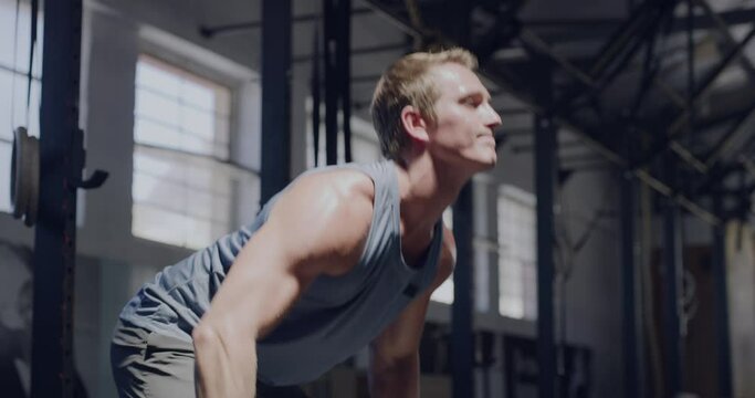 Muscular man lifting a barbell while doing bent over rows in a gym. Fit young bodybuilder staying focused while challenging himself by lifting heavy weights to gain muscle and endurance in a workout