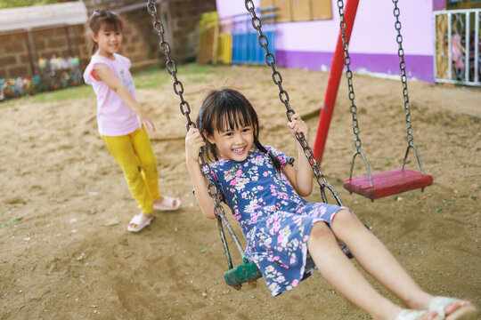 Kids having fun playing swing at the playground in the park. Joyful outdoor activity for children concept.	