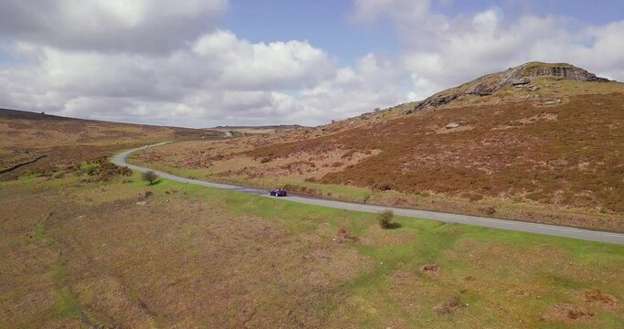 Dartmoor National Park moorland road and car passing in United Kingdom