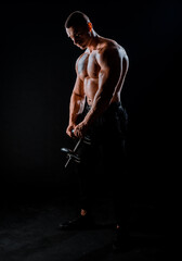 Fototapeta na wymiar Muscular male model bodybuilder doing exercises with dumbbells