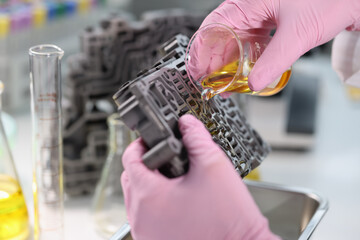 Scientist from chemical flask pours oil on gearbox valve body