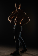 Silhouette of topless guy posing and flexing in studio while twisting