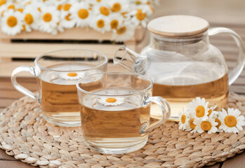 Closeup rustic breakfast chamomile organic tea with two glass cups and transparent teapot on wooden...