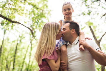 Father, mother with his daughter having fun outside in forest