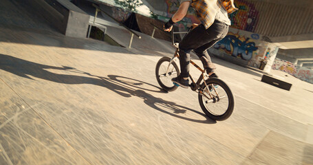 Young biker performing rail stunt at urban skate park. Rider racing on bmx.