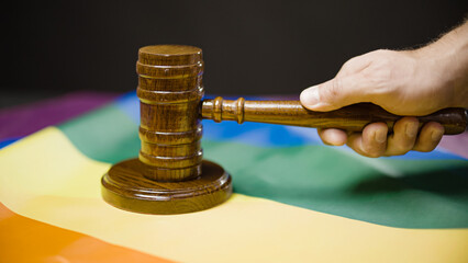 Judge hand hitting gavel against lgbt flag background, same-sex marriage legalization, law