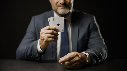 Smiling man in suit showing pair of aces while playing poker, luck and gambling