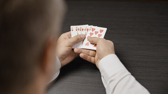Male poker player holding royal flush card combination in hands, successful game
