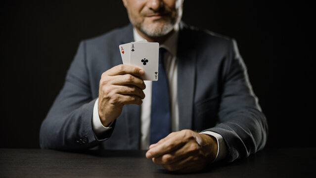 Smiling man in suit showing pair of aces while playing poker, luck and gambling - Powered by Adobe