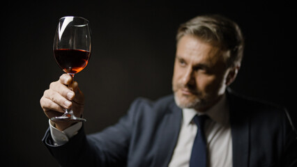 Bearded businessman in elegant suit drinking wine, enjoying flavor, degustation - obrazy, fototapety, plakaty