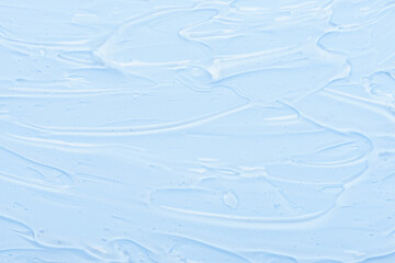 Transparent smeared gel cream serum with bubbles on blue background. Cosmetic skincare beauty product texture top view.