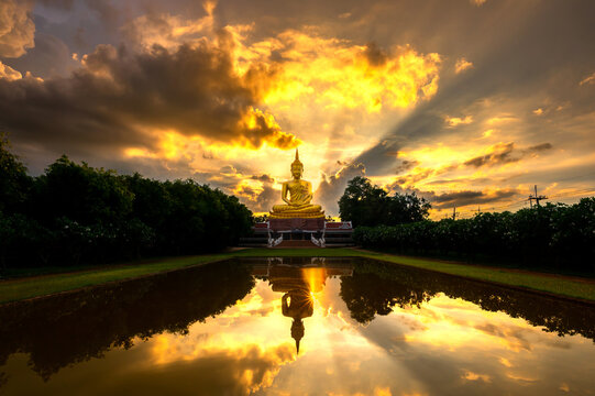 Beautiful Big Golden Buddha statue sunset sky in Thailand temple,khueang nai District, Ubon Ratchathani province, Thailand.Amazing Buddha image with sunny sky clouds.