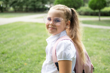 close up portrait of blonde schoolgirl in glasses white shirt with pink backpack back to school