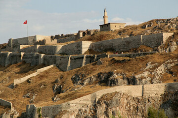 A view of Van Castle, which is located on a high rock, with mosque on its grounds, against a blue sky with clouds, in the Eastern Anatolia region of Turkey