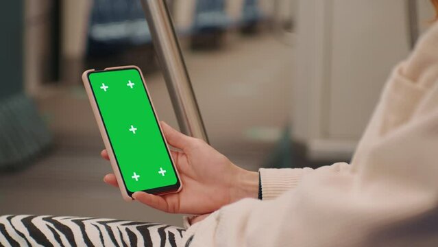 Woman enjoying a video on the cromakey smartphone on train. Female hands watching film on a train. Technology era. Close-up hand holding Smartphone with Green Screen Mock Up.
