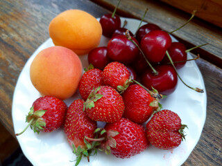 Strawberry, cherries and apricots on a white plate, summer food, fruit and berries.