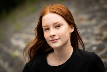 Red haired twelve year old girl with freckles posing with a city bokeh background
