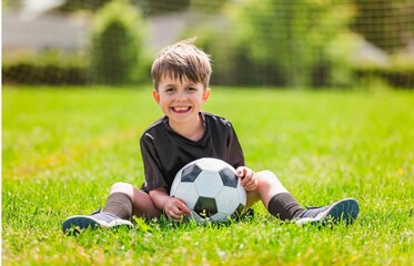 Cute boy playing football enjoying sport game outside