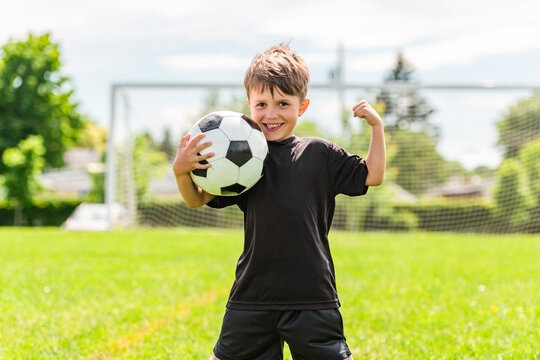 Cute boy playing football enjoying sport game outside