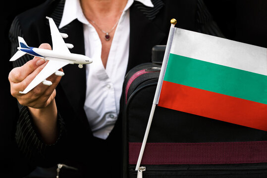  business woman holds toy plane travel bag and flag of Bulgaria
