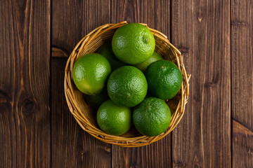 Limes in the basket with copy space on wooden background.