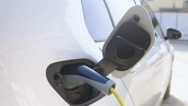 Female hands disconnect and show DC fast charging socket Europe type two. Business woman holding an electric car plug of EV. Woman plugging an electric car or EV at home electric charging station