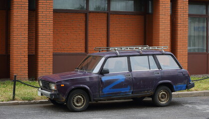 An old lilac Soviet car at the red brick wall, Podvoysky Street, St. Petersburg, Russia, July 2022