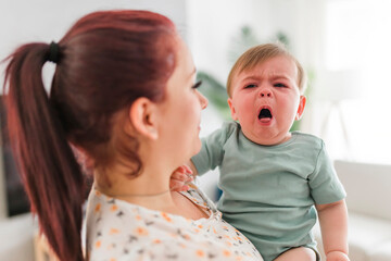 mother holding child baby on the living room. The baby is sick having some cough